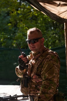 A military major employs a Motorola radio for seamless communication with his fellow soldiers during a tactical operation, showcasing professionalism and strategic coordination photo