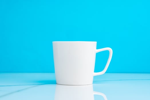 Ceramic mug on blue studio background close up photo