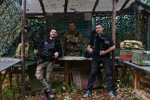 Two videographers collaborate seamlessly, capturing moments with a military major at his base, illustrating a harmonious blend of technology, media, and military communication in the production of a photo