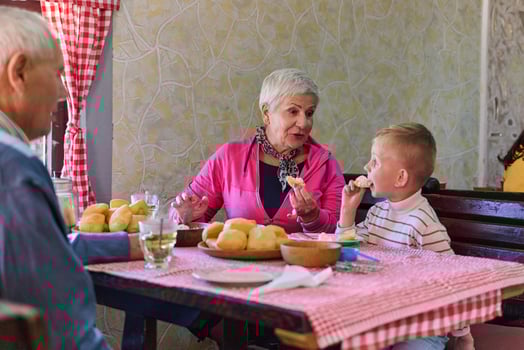Elderly couple shares a heartwarming meal with their grandchild, creating cherished memories and enjoying the simple pleasures of family bonding in the peaceful countryside photo