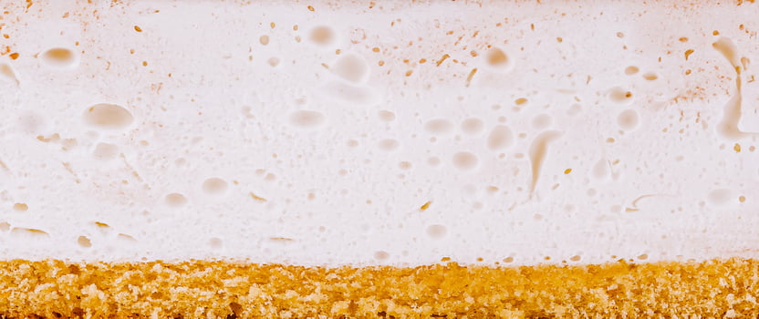 White cream filling on top of golden sponge cake texture background photo