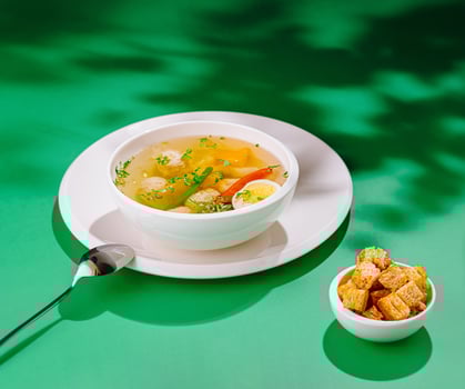 Chicken soup with meatballs and vegetables on green background photo