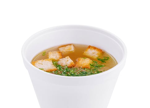Delicious broth with croutons in a white bowl on white background photo