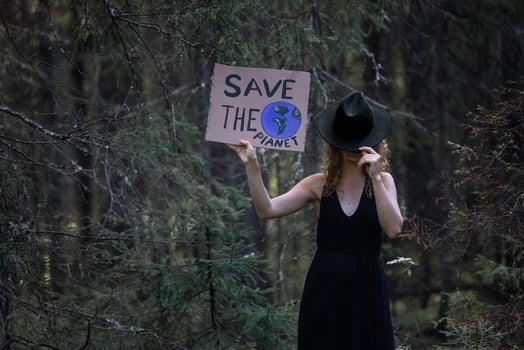 Pretty young woman holding a cardboard banner in hands in a hat in the woods. photo