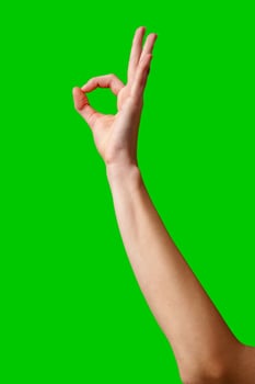 Hand Gesturing Okay Sign Against a Vibrant Green Background photo