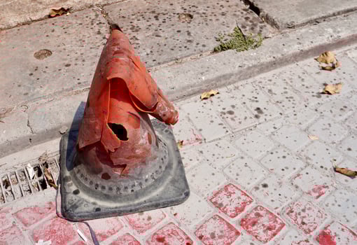 One old and broken orange plastic traffic cone object isolated on horizontal ratio brick stone flooring background. photo
