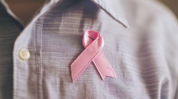 A pink ribbon is on a man's shirt photo
