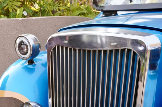 Vintage old styled blue metal car body front part design isolated on horizontal ratio outdoor environment background. photo