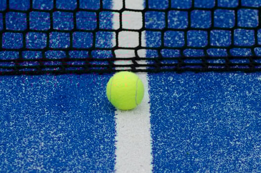 blue paddle tennis court and net with a ball, racket sports concept photo