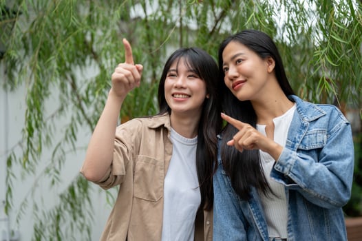 Two attractive Asian female friends are enjoying the view in a lush home garden. photo