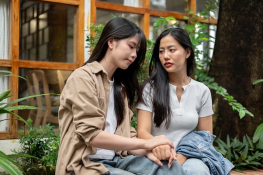 A caring woman is comforting and encouraging her sad friend as they have a conversation in a garden. photo