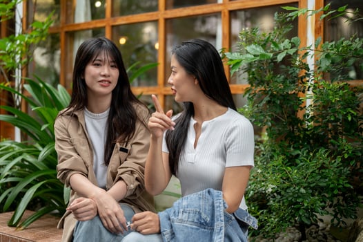 Two young Asian female friends are engaged in conversation in a beautiful garden. photo