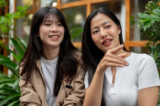 Two young Asian female friends are engaged in conversation in a beautiful garden. photo
