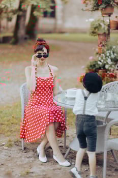 Beautiful woman in red dress looking over sunglasses at her little son in an outdoor cafe photo