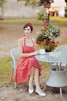 Woman in red dress drinking coffee at table, vintage style retro portrait photo