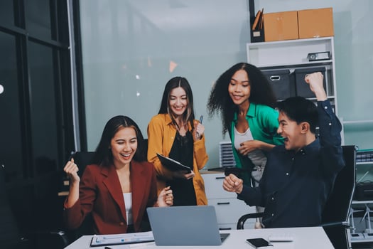 Young corporate employees sitting in office looking at laptop screen reading good news excited happy team diverse people celebrating victory win command success excellent result professional teamwork photo