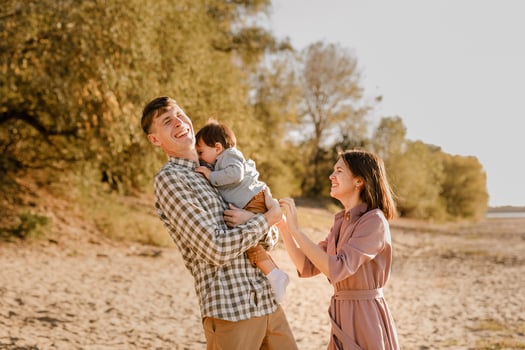 Happy family walking on the road in the park. Father, mother holding baby son on hands and going together. Rear view. Family Ties concept. photo