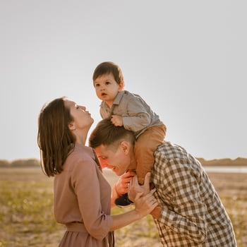 Happy family walking on sandy beach of river. Father, mother holding baby son on hands and going together. Rear view. Family Ties concept. photo