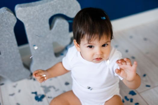One year old baby boy celebrates birthday near silver letters ONE on blue background with stars photo