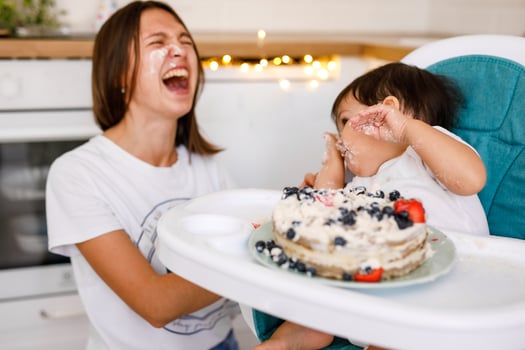 Happy mother with one year old baby celebrating with first birthday with white kitchen on background photo