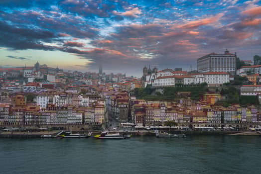 View of Porto, Portugal, featuring the colorful Ribeira district, Clerigos Tower, and Episcopal Palace. Traditional Rabelo boats dot the Douro River under dramatic clouds. photo