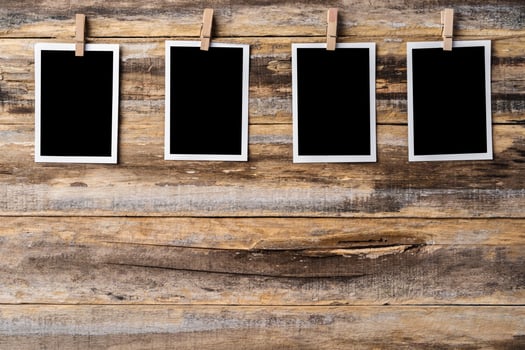 Paper blank photo frames hanging on wooden wall