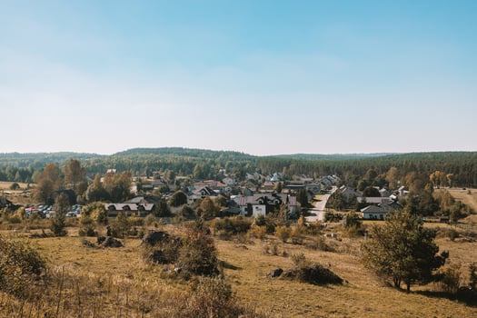 Beautiful summer sunrise in the mountains. Wavy fields and village. Panorama with countryside gravel road among spring fields and old oak tree and village on horizon photo