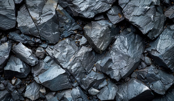 A close up of a pile of black rocks. The rocks are large and rough, with some of them having a shiny, metallic appearance. Scene is one of ruggedness and strength photo