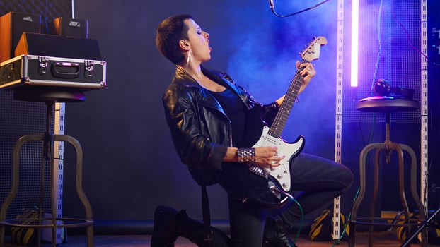 Female musical performer in a leather jacket plays electric guitar, delivering a fierce energetic music performance that captivates audience with her bold grunge style. Music lover. Camera A. photo