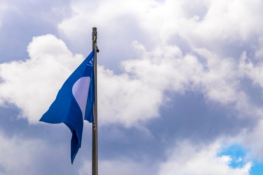Blue flag with cloudy windy sky at certificated beach in Mexico. photo