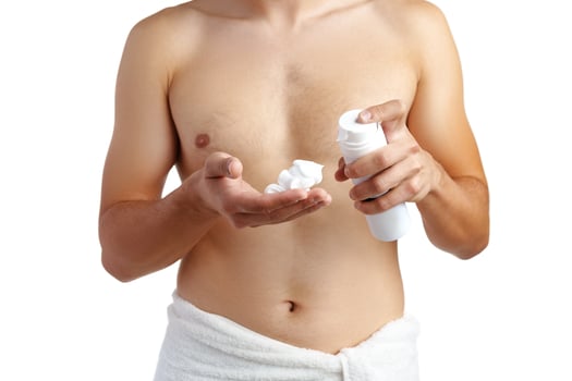 Unrecognizable man holding shaving foam in hands against white background photo