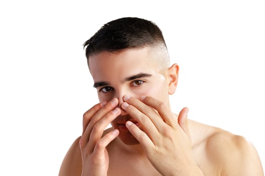 Young man standing shirtless and touching his face with hands photo