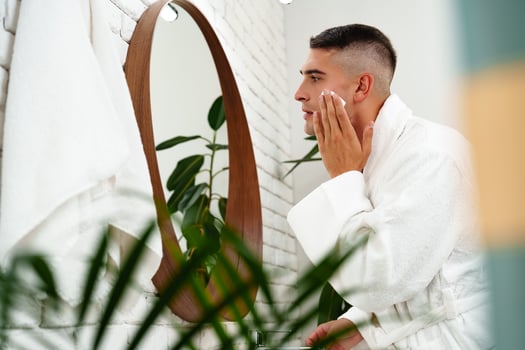 Reflection of a young man shaving in bathroom mirror close up photo