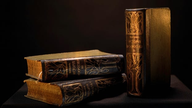 Vintage books with dark leather binding and patterns on isolated background. Stock footage. Old book with simple gilded patterns on cover photo