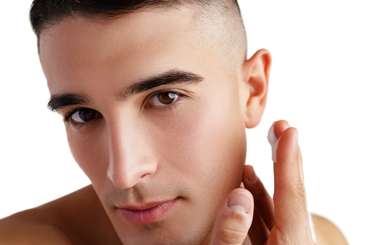 Young attractive brunet guy with perfect skin touching chin on white background photo