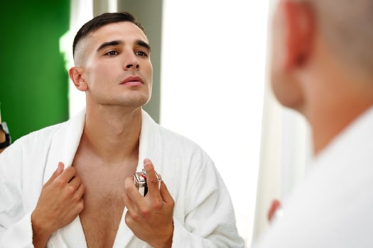 Handsome young man applying perfume in the bathroom photo
