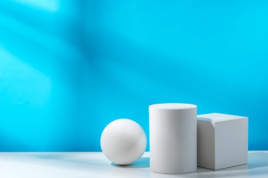 Three geometric shapes arranged on a table against a bright blue background during daytime lighting photo