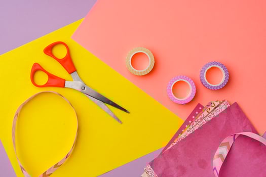 Scissors and decorative tape on colorful craft paper in a bright workspace photo
