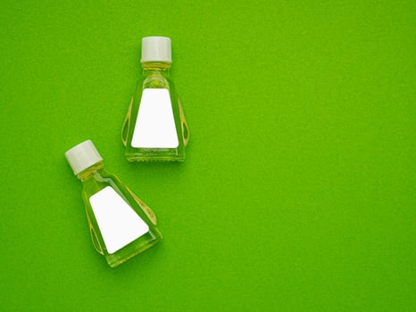 Small bottle containers with blank labels for branding mockup isolated on a green background. photo