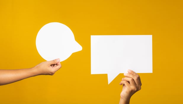Hand holding of an empty white speech bubble against a yellow background. photo