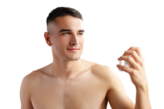 Handsome young man applying perfume on white background photo