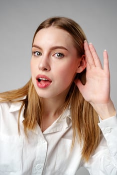 Woman in White Shirt Listening With Hand to Ear photo