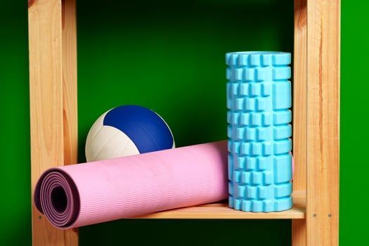 Shelves with different sports equipment against green wall photo