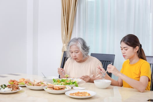 Mother and adult daughter eating meal together, Senior woman and daughter having breakfast in morning together photo