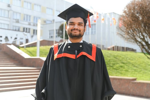 Handsome indian graduate in graduation glow with diploma photo