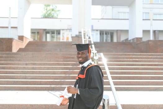 I have finally graduated. Happy young African man in graduation gowns holding diploma photo