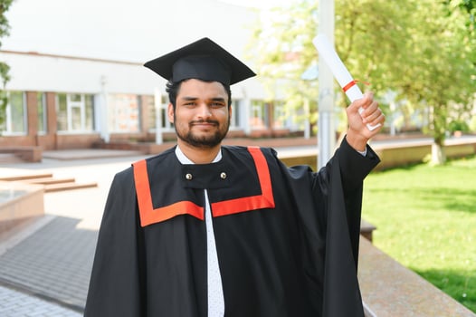 Handsome indian graduate in graduation glow with diploma photo