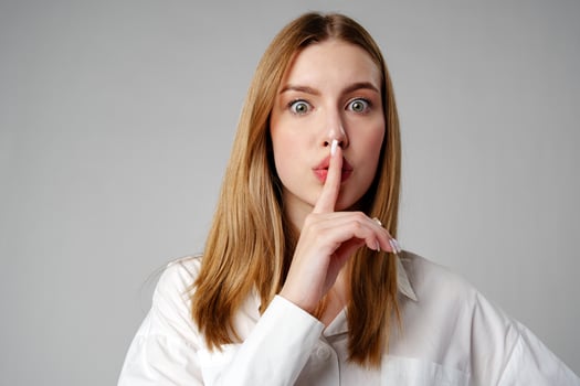Young Woman Making a Hush Gesture on gray background photo