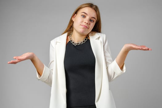 Young Woman Expressing Confusion With Hands Raised Against a Grey Background photo