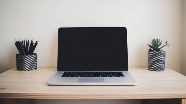 A laptop sits on a wooden desk with a plant and pencils photo